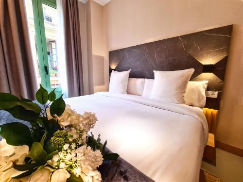 una habitación de hotel con una cama con sábanas blancas y flores en Hotel Casa Gardenia, en Barcelona