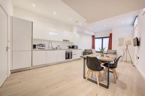 une cuisine et une salle à manger avec une table et des chaises dans l'établissement GuestReady - Modern Luxury near Tower Bridge, à Londres