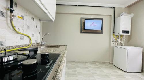 a kitchen with a sink and a tv on the wall at Ayyıldız Pansiyon Apart in Degirmen