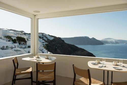 two tables and chairs with a view of the ocean at Canaves Ena - Small Luxury Hotels of the World in Oia