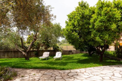 two chairs sitting in a yard with trees at Apartments Vasileiou Suite 4 in Preveza