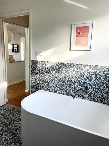 a bathroom with a white tub and black and white tiles at Stylish Shack Falcon Bay in Wannanup
