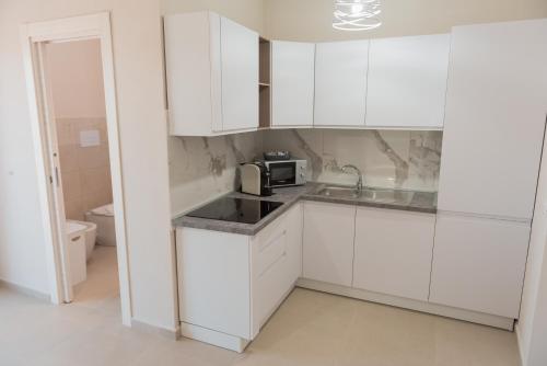 a white kitchen with a sink and a microwave at Casa Vacanza Merguli d'Oro in Siculiana