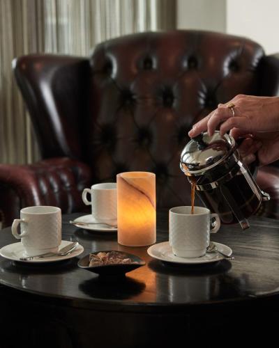 a woman is pouring coffee into cups on a table at Montra Hotel Sabro Kro in Sabro