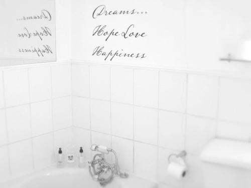 a bathroom with a white tiled wall with writing on the wall at The Lighthouse Guesthouse in Colesberg
