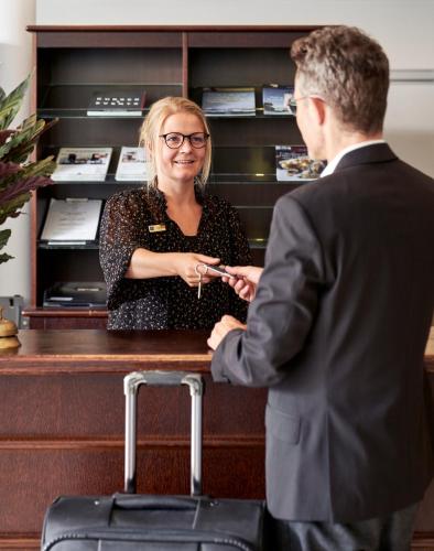 a man and a woman standing at a cash register at Montra Hotel Sabro Kro in Sabro