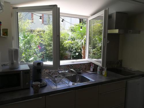 - un comptoir de cuisine avec évier et 2 fenêtres dans l'établissement Charmant studio avec jardin, à Toulouse