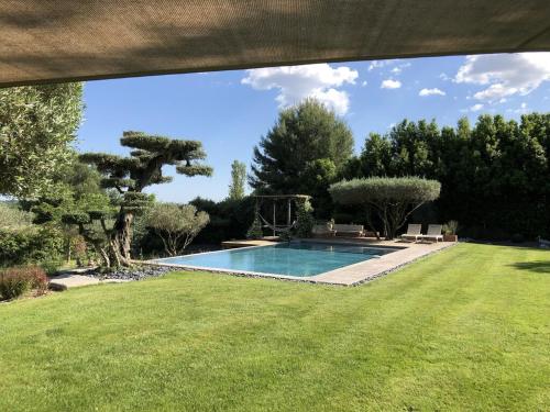 - une piscine dans une cour avec une pelouse verdoyante dans l'établissement Bastide Languedocienne de Standing - Pézenas LE CLOS DE L'AMANDIER, à Pézenas