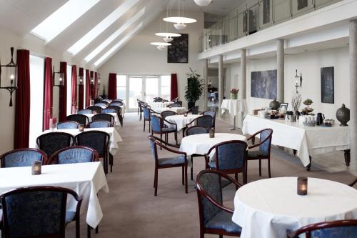 una fila de mesas en un restaurante con mesas y sillas blancas en Montra Hotel Sabro Kro, en Sabro