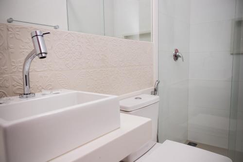 a white bathroom with a sink and a toilet at Augusta Hotel in João Neiva