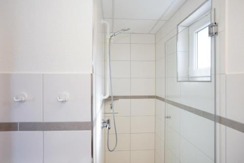 a white bathroom with a shower and a window at CVJM Freizeithaus MS Waterdelle in Borkum