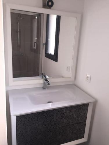 une salle de bain avec un lavabo et un miroir dans l'établissement L étoile de mer logement 2, à Sainte-Marie-la-Mer