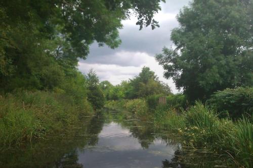 a river with trees and grass on the side at Tank Barn at Brook House, Nestled in the Welsh Hills, a delightful retreat in Welshpool