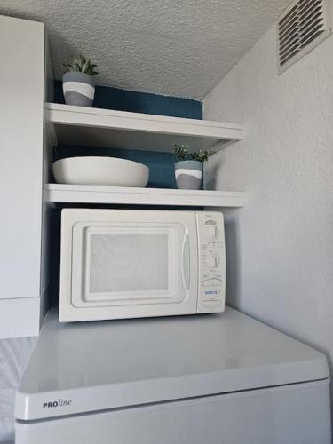 Un four micro-ondes blanc est installé au-dessus d'un réfrigérateur. dans l'établissement Joli & Cosy ! 4 Personnes, à Gruissan