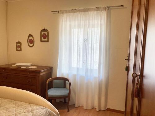 a bedroom with a window with a chair and a dresser at Al Civico 40 in Fai della Paganella