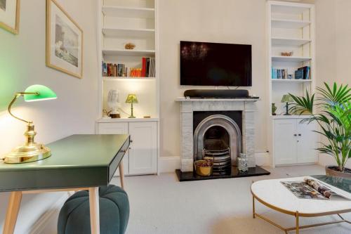 a living room with a fireplace and a tv at Bright Camberwell Georgian Apartment in London