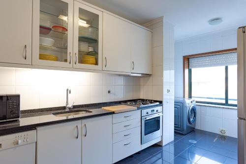 a kitchen with white cabinets and a washer and dryer at Retreat Hattie's Beach in Arcozelo