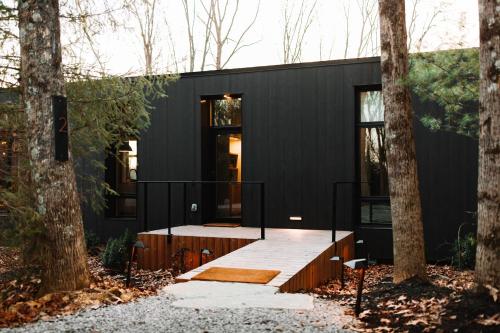 a black house with a deck in the woods at Idyll Reserve - Hocking Hills in South Bloomingville