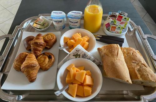 un vassoio con prodotti per la colazione, pane e succo d'arancia di Chambre d'Hôtes Les Bacquerins a Sainte-Hélène