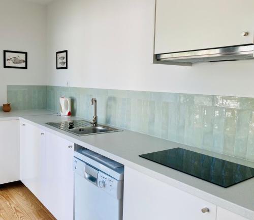 a white kitchen with a sink and a counter top at Villa 53 Beach House Médoc in Le Verdon-sur-Mer