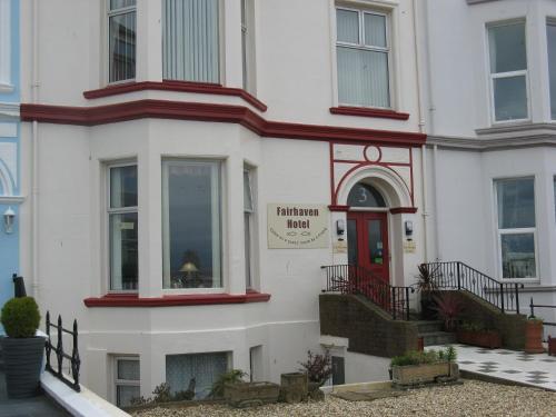 a white building with a red door at Fairhaven Hotel in Llandudno