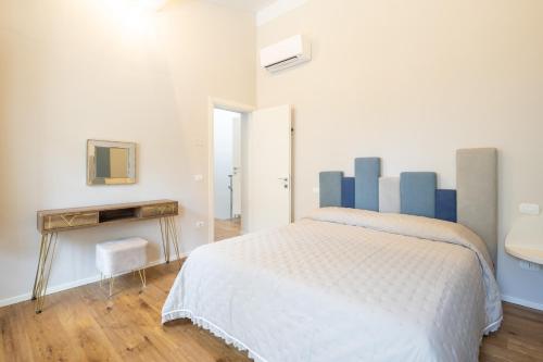 a white bedroom with a bed and a table at Villetta Marice by VacaVilla in Stabbia