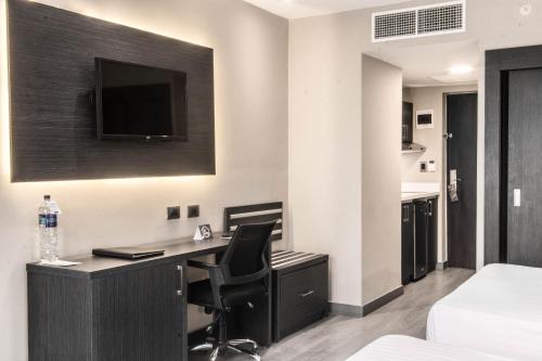 a hotel room with a desk with a television on the wall at W&P Santo Domingo in Santo Domingo