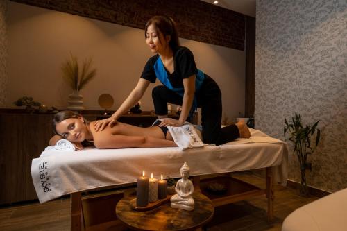 a woman sitting on a bed with a woman getting a massage at Sky Blue Hotel & Spa in Ploieşti