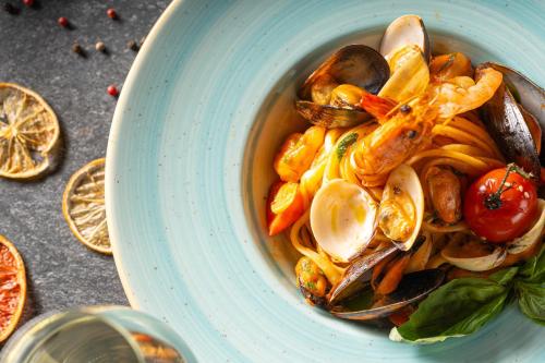 a bowl of seafood pasta with shrimp and vegetables at Sky Blue Hotel & Spa in Ploieşti