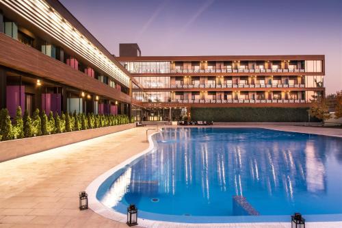 une piscine d'hôtel en face d'un bâtiment dans l'établissement Sky Blue Hotel & Spa, à Ploieşti