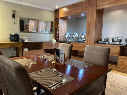 uma sala de jantar com uma mesa de madeira e cadeiras em Lotus by Serendib em Blantyre