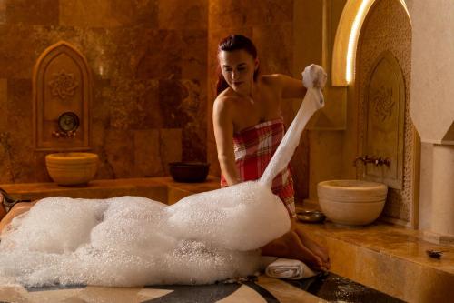 a woman standing in a bath room with a balled up swan at Sky Blue Hotel & Spa in Ploieşti