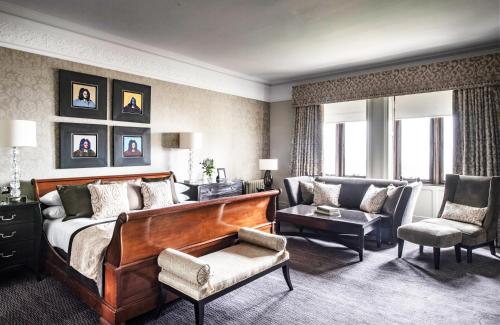 a bedroom with a bed and a couch and a chair at Nutfield Priory Hotel & Spa in Redhill