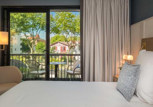 a hotel room with a bed and a balcony at Hôtel Arcanse by Inwood Hotels in Arcachon