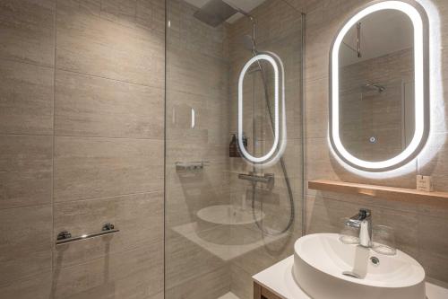a bathroom with a shower and a sink and a mirror at Hôtel Arcanse by Inwood Hotels in Arcachon