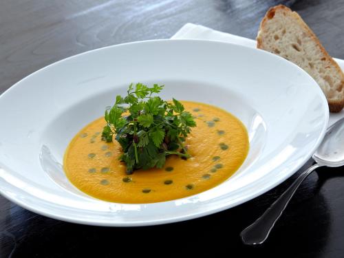 a white plate with a bowl of soup on a table at Montra Hotel Sabro Kro in Sabro