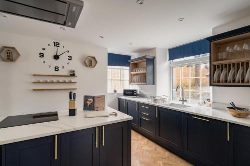 a kitchen with blue cabinets and a clock on the wall at Crossriggs- Beautiful Detached Home in Windermere
