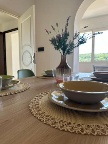 a dining room table with plates and a vase with flowers at Dimora Valentina in Tricase