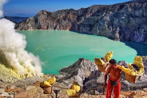 a man standing on top of a mountain with a body of water at Ijen Farmer Homestay in Banyuwangi