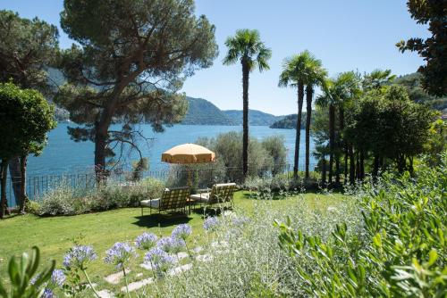 a garden with a table and chairs and a view of the water at Passalacqua in Moltrasio