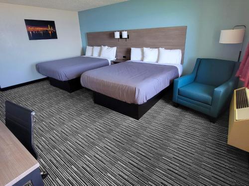 a hotel room with two beds and a blue chair at Bavarian Haus Lakefront Inn in Saint Ignace