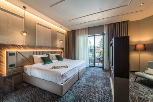 a hotel room with a large bed and a chair at Sky Blue Hotel & Spa in Ploieşti