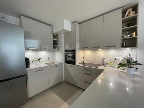 une cuisine avec des armoires blanches et des appareils électroménagers blancs dans l'établissement Modern family 3 bedroom apartment in the center of Maisons-Laffitte, à Maisons-Laffitte