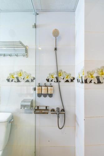 a shower stall in a bathroom with flowers on the wall at Rockmila Hotel in Phu Quoc