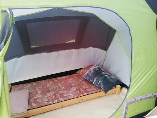 ein grünes Zelt mit einem Bett in der Mitte in der Unterkunft Trijų žvaigždučių palapinė Vilniuje in Vilnius