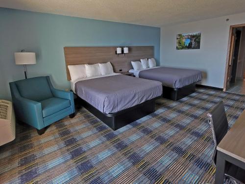 a hotel room with two beds and a blue chair at Bavarian Haus Lakefront Inn in Saint Ignace