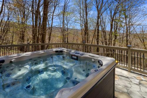 a jacuzzi tub on a deck with trees at Pipers Paradise in Beech Mountain