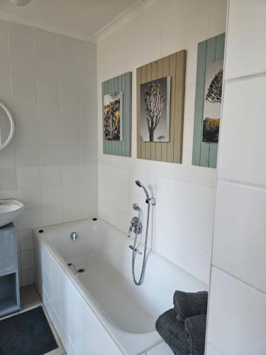 a white bathroom with a tub and three pictures on the wall at Lady Smith Self Catering Units in Bloemfontein