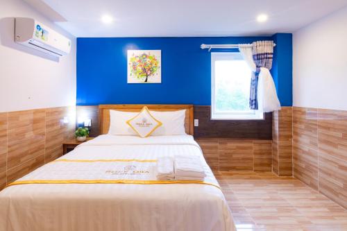 a bedroom with a large bed with a blue wall at Rockmila Hotel in Phu Quoc