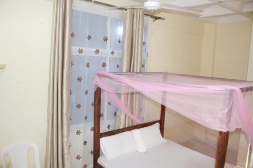 a bedroom with a bed with a pink canopy at Booster Villa Mtwapa in Mtwapa